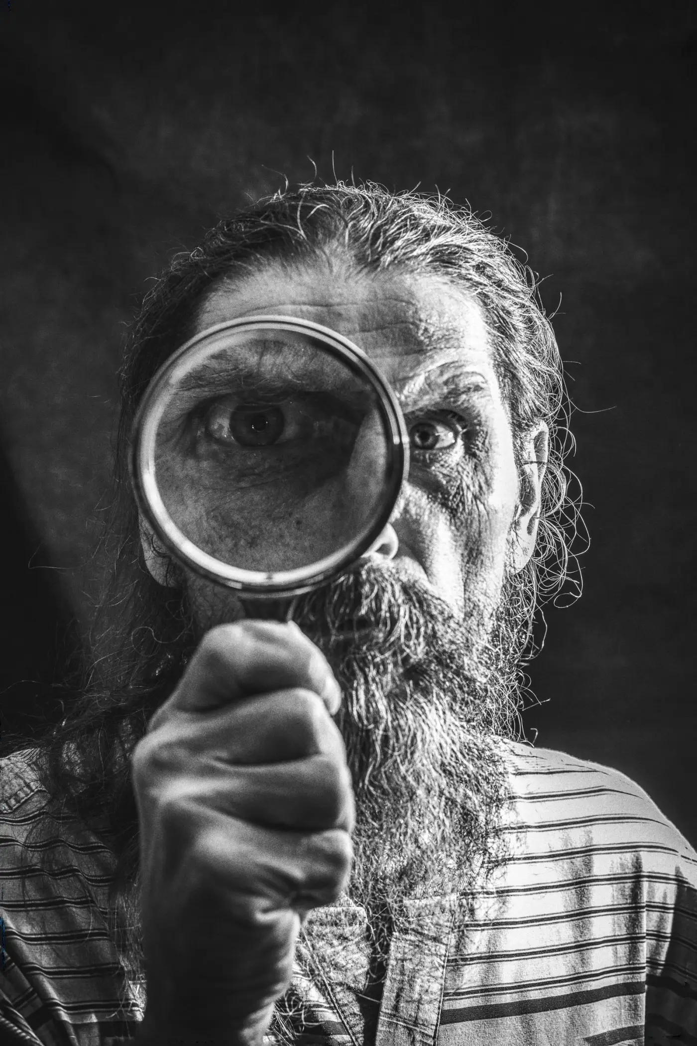 A man studying something closely through a magnifying glass